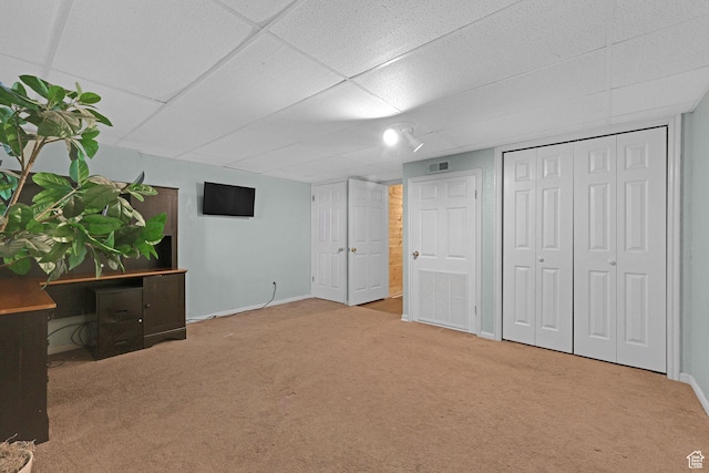 unfurnished bedroom featuring carpet, visible vents, a drop ceiling, and baseboards