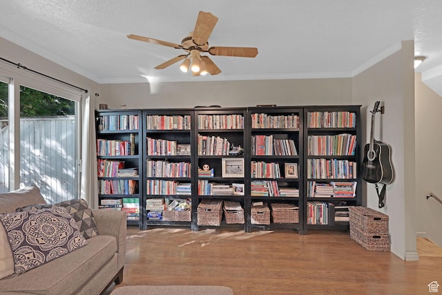 living area with wood finished floors, ceiling fan, baseboards, and ornamental molding