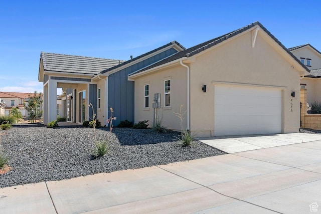 5648 S Adobe Sun Dr, St George, UT 84790 - view of front of home featuring board and batten siding, an attached garage, driveway, and stucco siding
