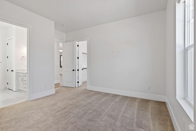 5648 S Adobe Sun Dr, St George, UT 84790 - unfurnished bedroom featuring baseboards, light carpet, ensuite bathroom, a walk in closet, and multiple windows