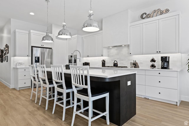 1624 W Chandler Dr, St George, UT 84770 - kitchen featuring an island with sink, decorative backsplash, light wood-type flooring, a kitchen bar, and recessed lighting