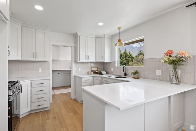 205 S Highland Dr, Santaquin, UT 84655 - kitchen featuring a peninsula, white cabinetry, light countertops, a sink, and range with gas cooktop