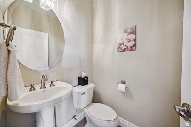 half bathroom with a sink, toilet, and baseboards