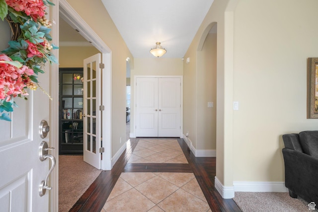 foyer featuring arched walkways, baseboards, and dark wood finished floors
