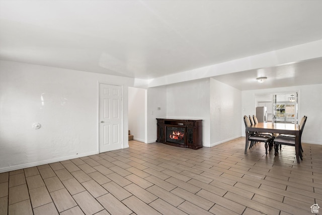 interior space with a lit fireplace, wood finished floors, and baseboards