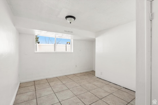 empty room featuring light tile patterned flooring, baseboards, and visible vents