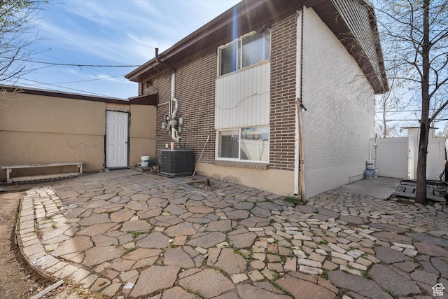 back of house featuring brick siding, fence, central air condition unit, and a patio area