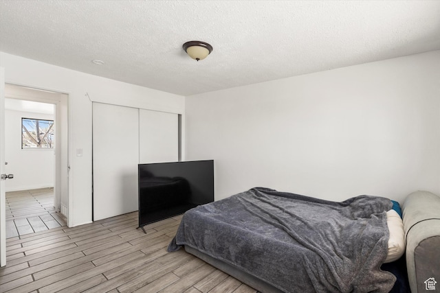 bedroom featuring a closet, light wood-style floors, and a textured ceiling
