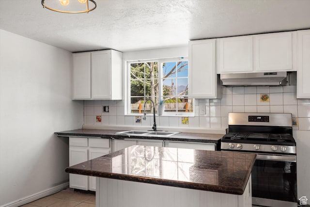 kitchen with white cabinets, gas range, under cabinet range hood, a sink, and backsplash