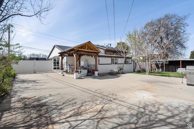 rear view of house featuring a gazebo, fence, a patio, and stucco siding