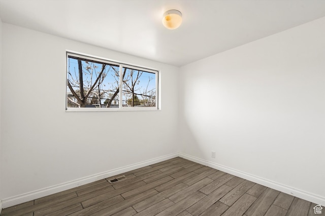 spare room featuring visible vents, baseboards, and wood finished floors