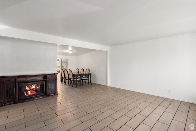 living area with light wood finished floors, baseboards, and a warm lit fireplace