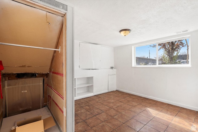 interior space with baseboards, tile patterned floors, a textured ceiling, visible vents, and built in shelves