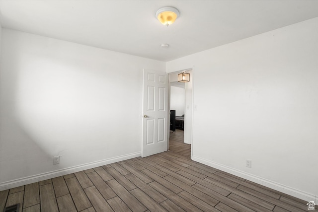 empty room featuring visible vents, baseboards, and wood finished floors