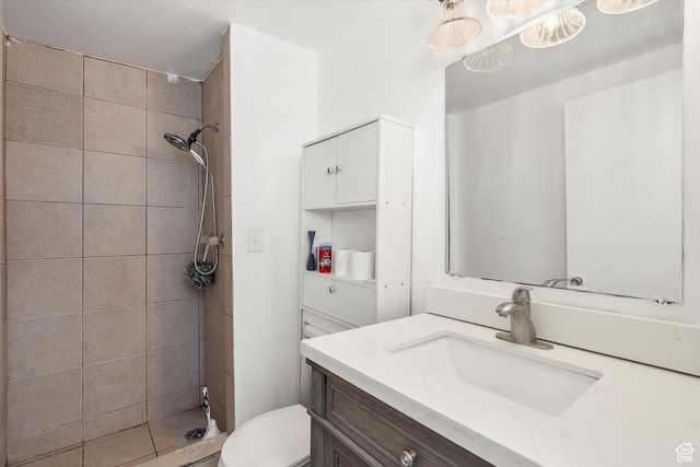 full bathroom featuring vanity, a tile shower, and toilet