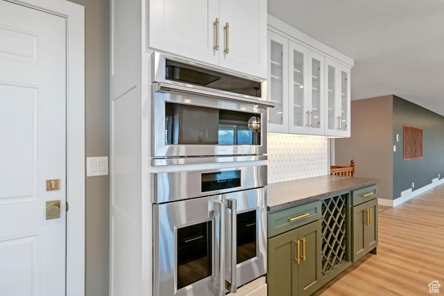 816 E 16th Ave, Salt Lake City, UT 84103 - kitchen featuring green cabinetry, white cabinetry, baseboards, light wood-type flooring, and glass insert cabinets