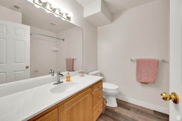 bathroom featuring vanity, baseboards, toilet, visible vents, and wood finished floors