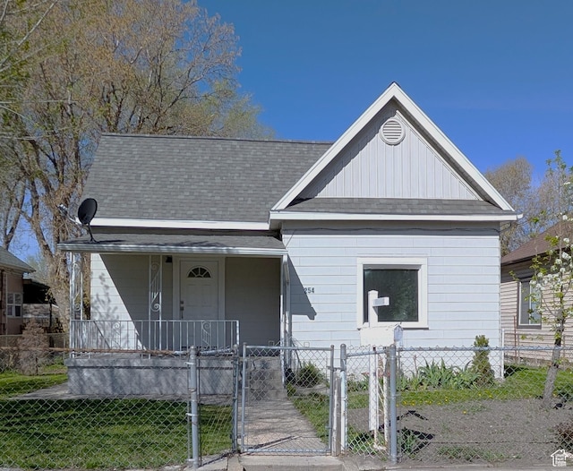 bungalow-style house with a porch, roof with shingles, a fenced front yard, and a gate