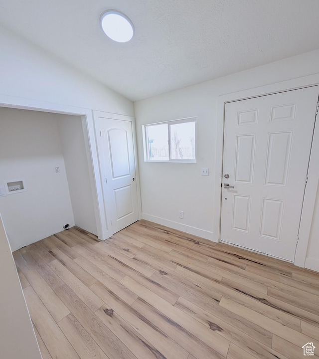 foyer featuring baseboards, light wood-type flooring, and lofted ceiling