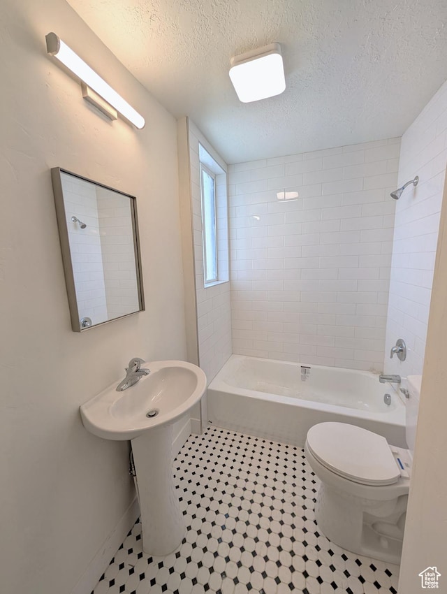 bathroom featuring bathing tub / shower combination, a textured ceiling, toilet, and tile patterned flooring