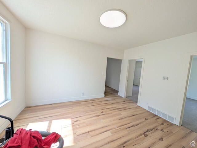 unfurnished room featuring visible vents, light wood-style flooring, baseboards, and a healthy amount of sunlight