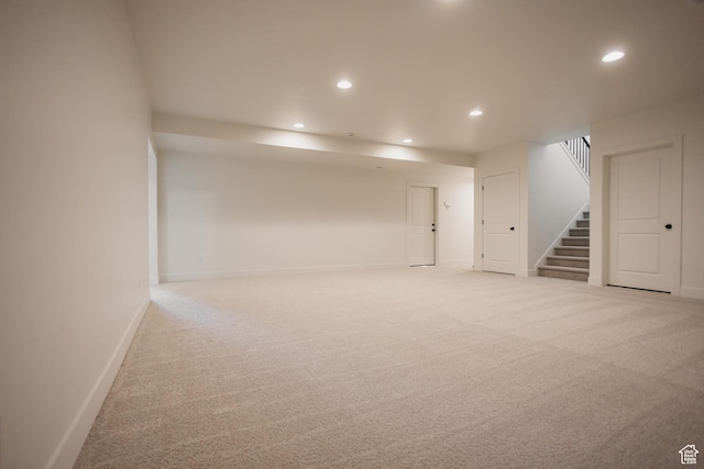 finished below grade area with light carpet, stairs, baseboards, and recessed lighting
