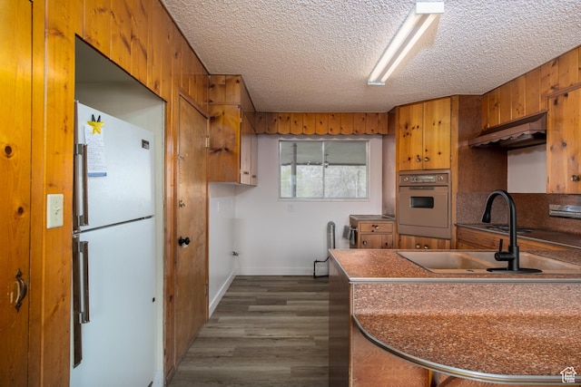 1520 Rushton St, Ogden, UT 84401 - kitchen featuring brown cabinetry, a textured ceiling, under cabinet range hood, and white appliances