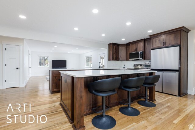 379 E 100 S, Kaysville, UT 84037 - kitchen featuring appliances with stainless steel finishes, dark brown cabinets, light wood finished floors, and a center island