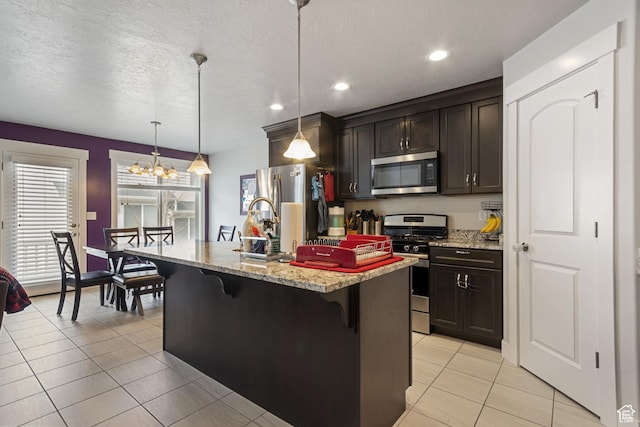 kitchen featuring light tile patterned floors, recessed lighting, a chandelier, appliances with stainless steel finishes, and a breakfast bar area