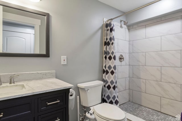 full bathroom with tiled shower, vanity, and toilet