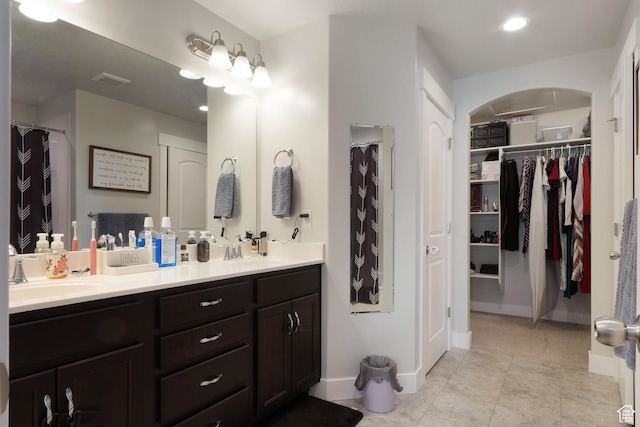 bathroom with a spacious closet, double vanity, visible vents, and a sink
