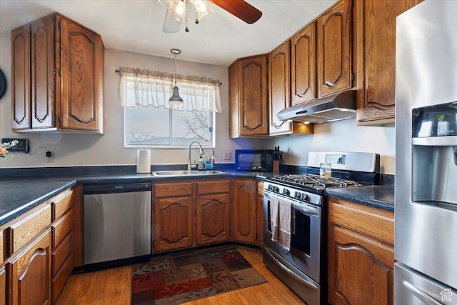 14883 S 3200 W, Bluffdale, UT 84065 - kitchen with under cabinet range hood, brown cabinets, a sink, and appliances with stainless steel finishes