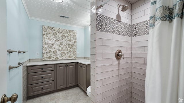 bathroom featuring a tile shower, crown molding, vanity, and visible vents
