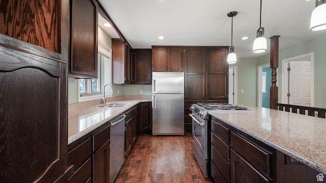 kitchen featuring a sink, appliances with stainless steel finishes, dark wood finished floors, dark brown cabinets, and light stone countertops