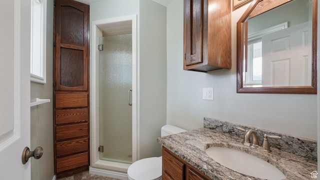 bathroom featuring a shower stall, vanity, and toilet