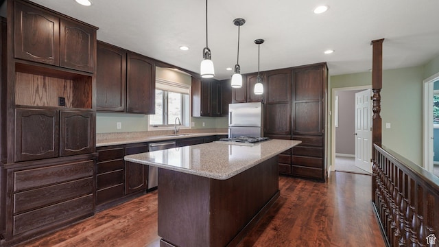 kitchen featuring a center island, dark brown cabinets, dark wood-type flooring, appliances with stainless steel finishes, and a sink