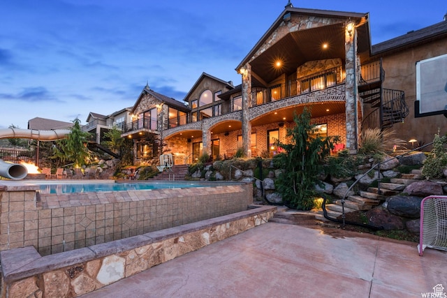 13879 S Standing Oak Dr E, Draper, UT 84020 - rear view of property featuring stairway, a patio, brick siding, an outdoor pool, and a balcony