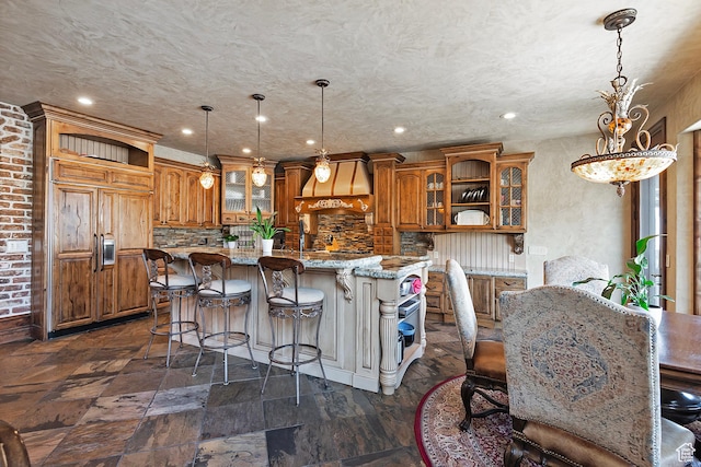 13879 S Standing Oak Dr E, Draper, UT 84020 - kitchen with brown cabinetry, a kitchen bar, glass insert cabinets, and a kitchen island