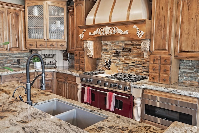 13879 S Standing Oak Dr E, Draper, UT 84020 - kitchen with premium range hood, brown cabinets, decorative backsplash, range with two ovens, and built in microwave