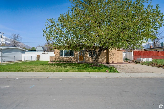 view of front of property featuring concrete driveway, fence, a front lawn, and brick siding