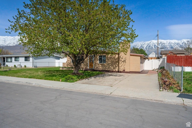 view of front of property with a mountain view, a front lawn, fence, and concrete driveway