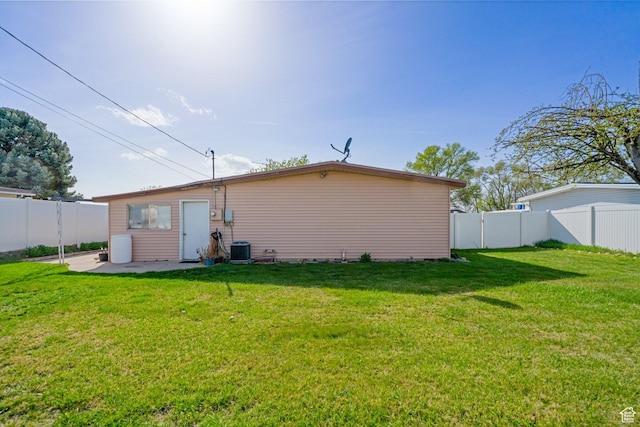 rear view of property with a patio, a fenced backyard, central AC, and a lawn