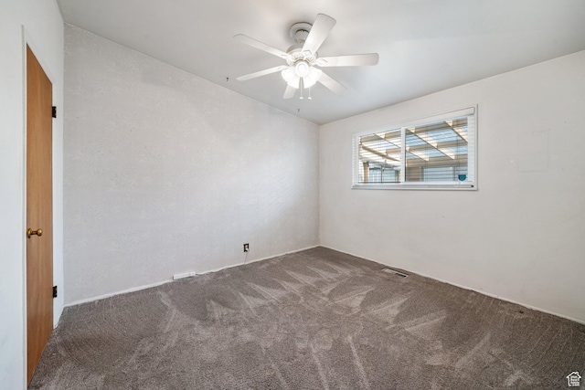empty room featuring visible vents, ceiling fan, and carpet
