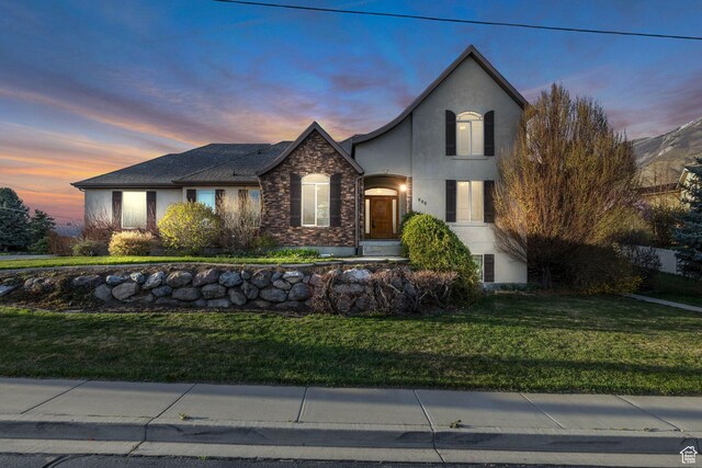 view of front facade with a front lawn, stone siding, and stucco siding