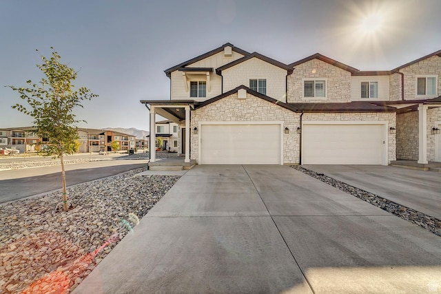view of front of house with stone siding, a residential view, a garage, and concrete driveway