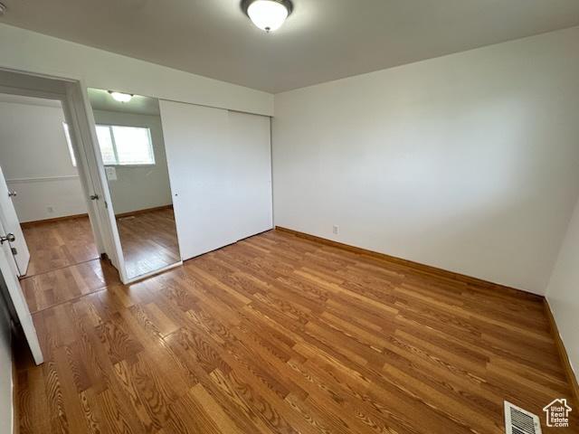 unfurnished bedroom with visible vents, a closet, baseboards, and wood finished floors
