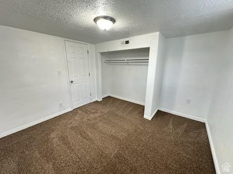 unfurnished bedroom with a closet, carpet flooring, a textured ceiling, and baseboards