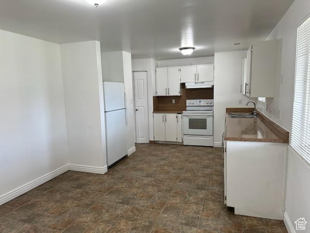 kitchen featuring white appliances, white cabinets, under cabinet range hood, stone finish floor, and a sink