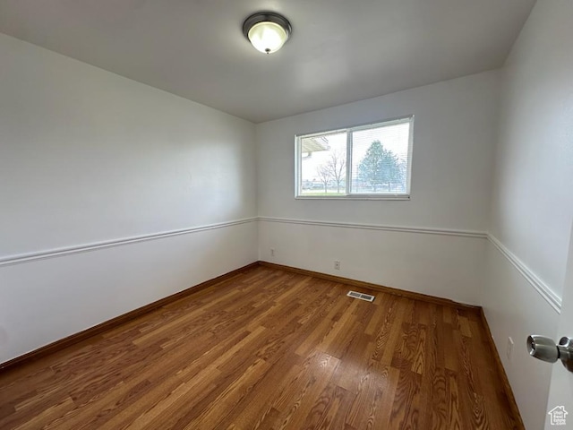 unfurnished room with visible vents, baseboards, and wood finished floors