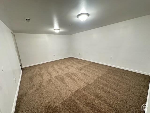 basement featuring visible vents, baseboards, and carpet flooring
